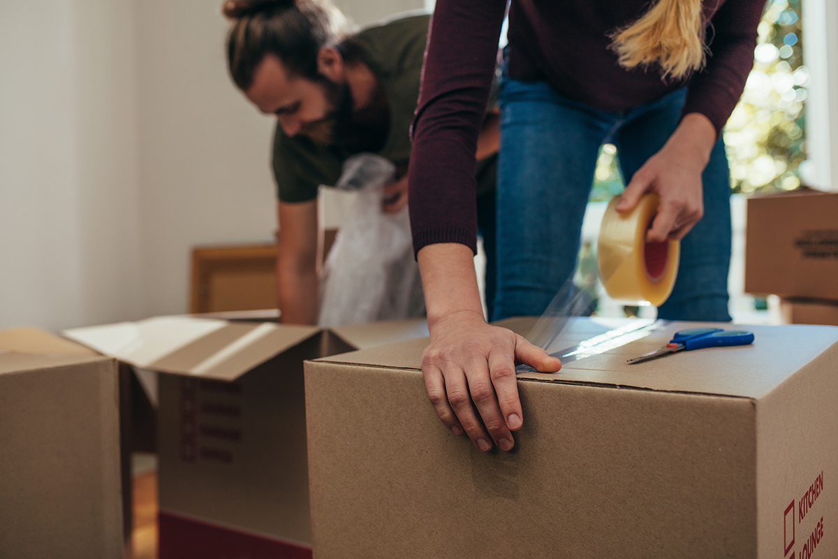 Close up of a woman applying adhesive tape on a packing box Dags för flytt